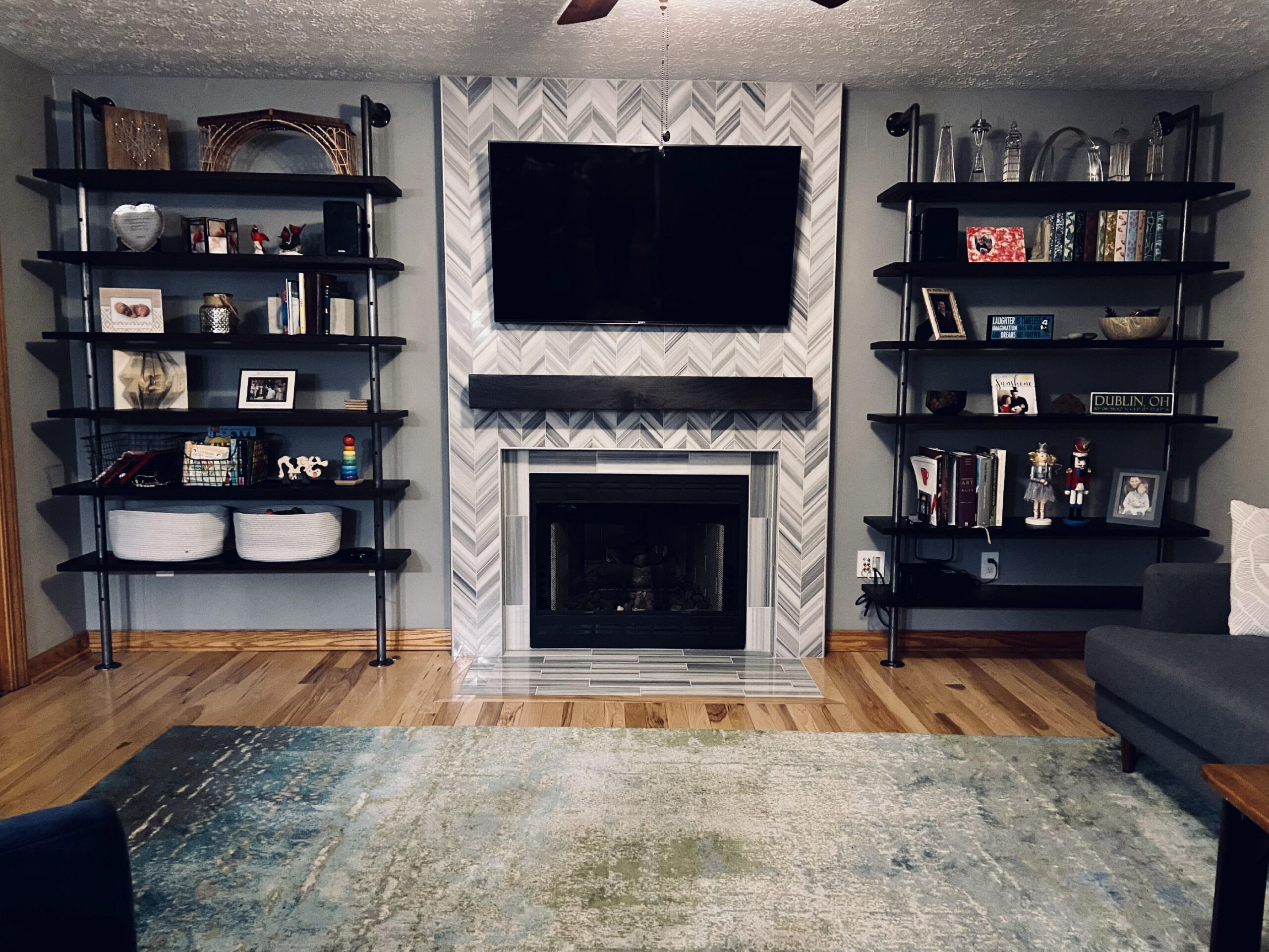 Living room with a fireplace, a television mounted on the wall, bookshelves filled with books, photo frames, toys