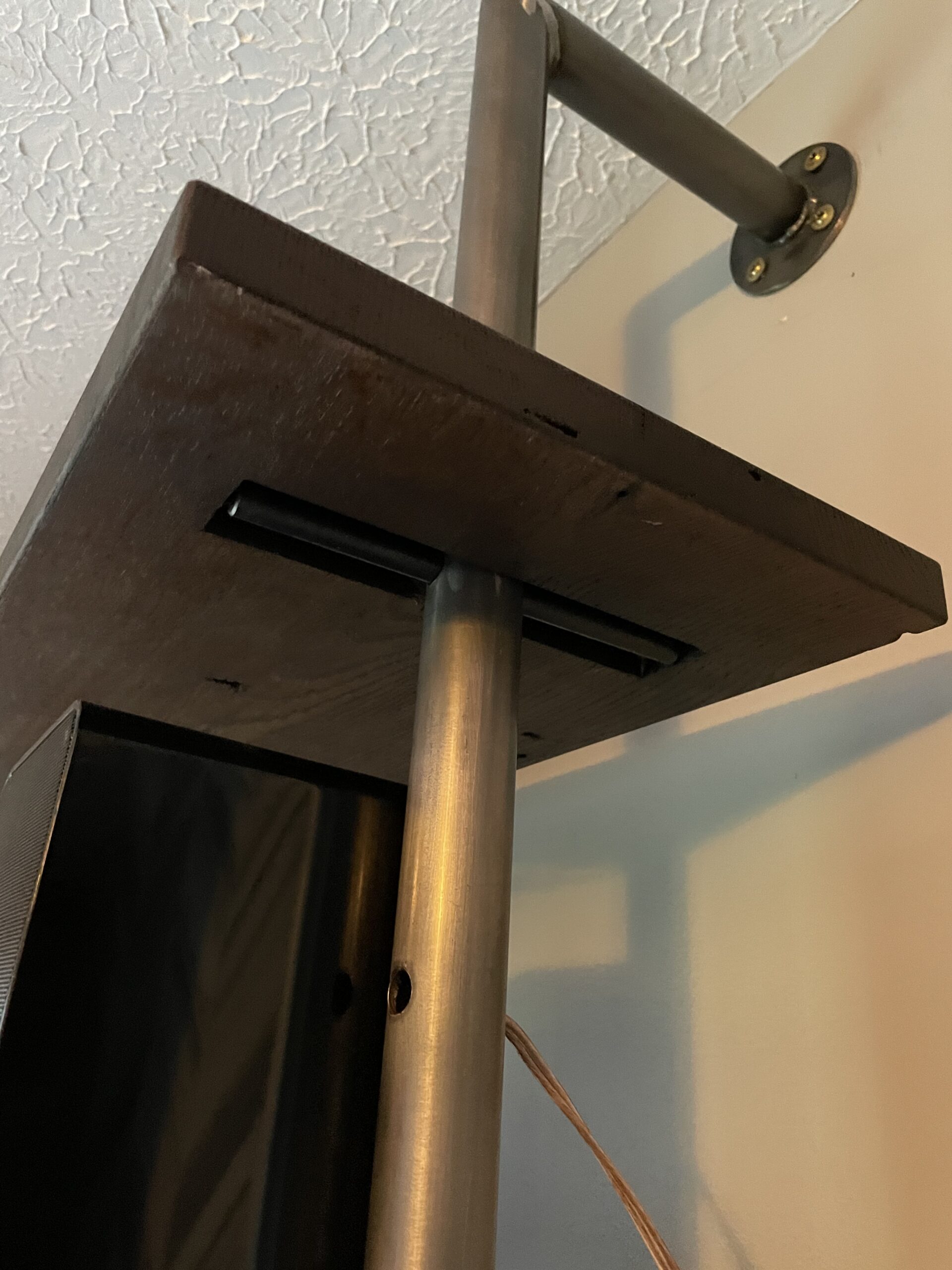 Close up of a metal pole with a speaker attached to it, mounted on a wall