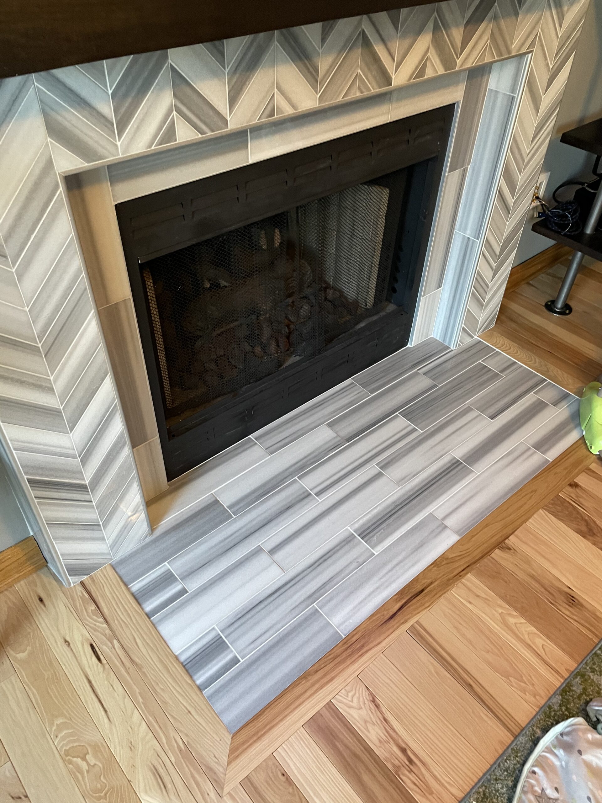 Fireplace with a herringbone tile surround and a wooden floor