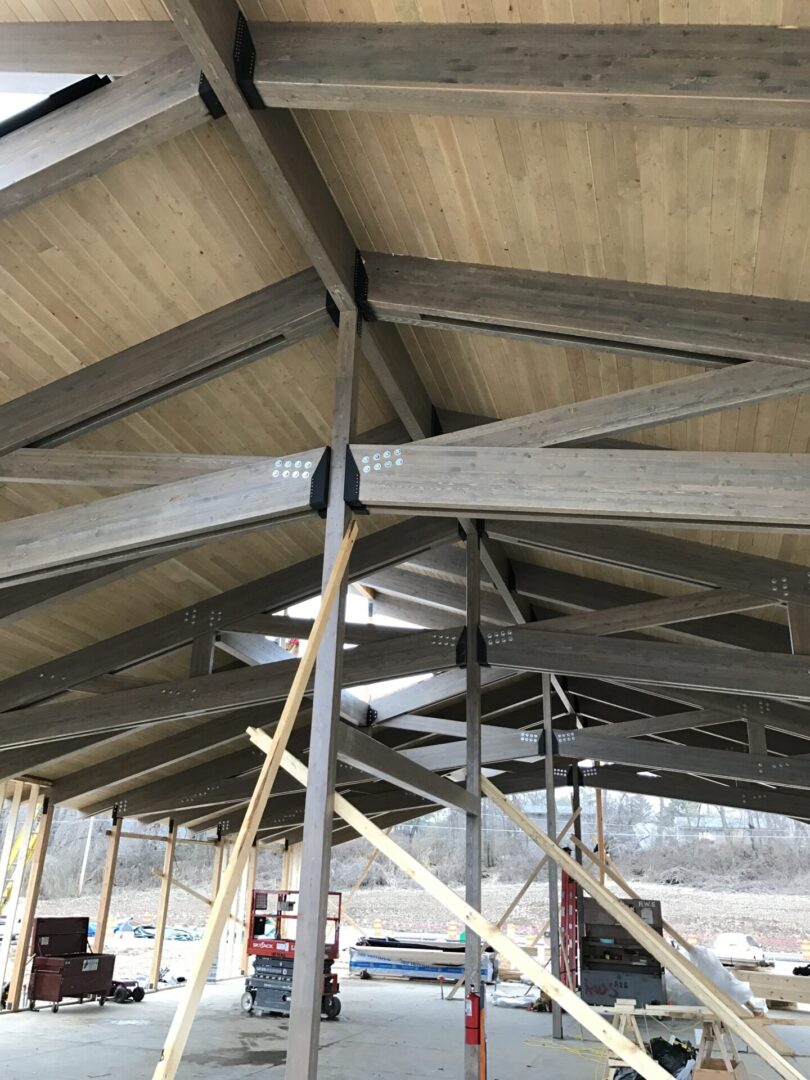 Large building under construction with a lot of wooden beams, vehicles, and other objects on the ground