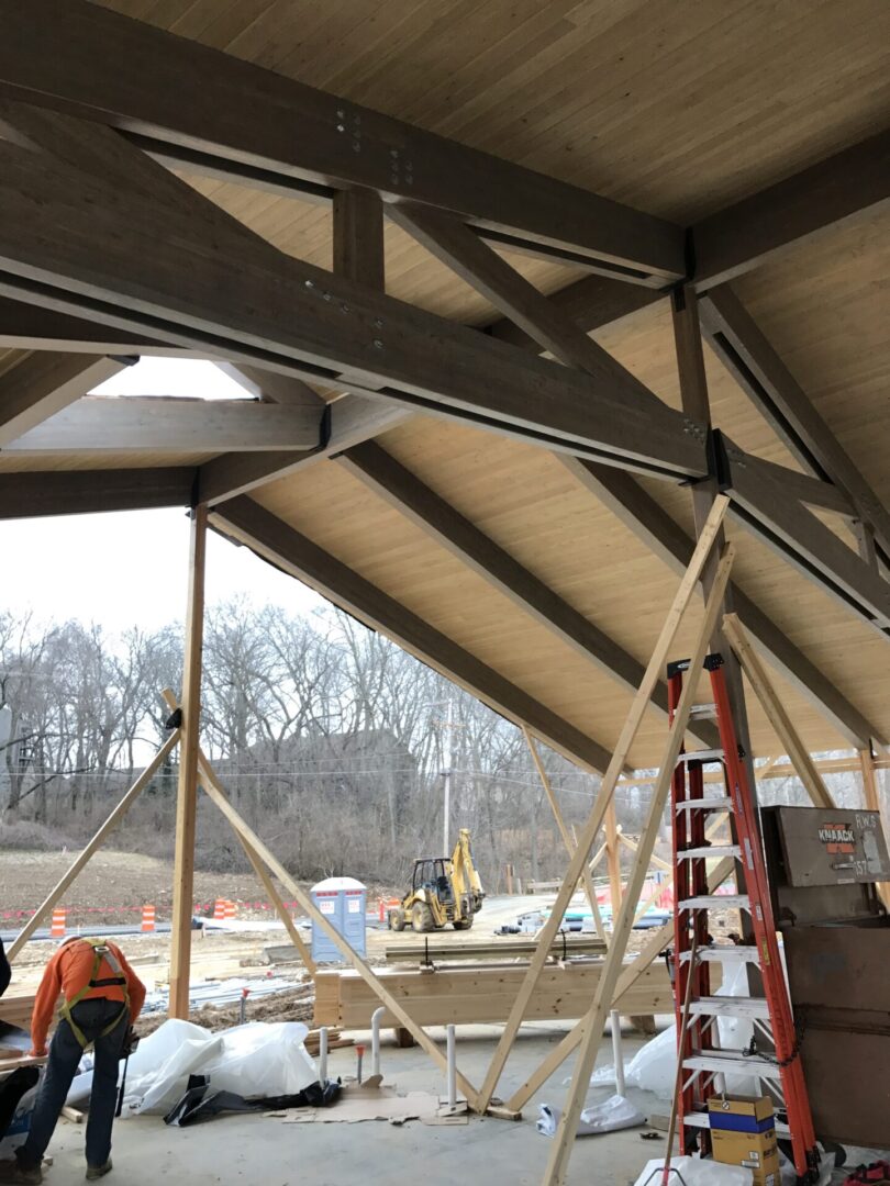 Two men working on a large wooden structure in a building under construction