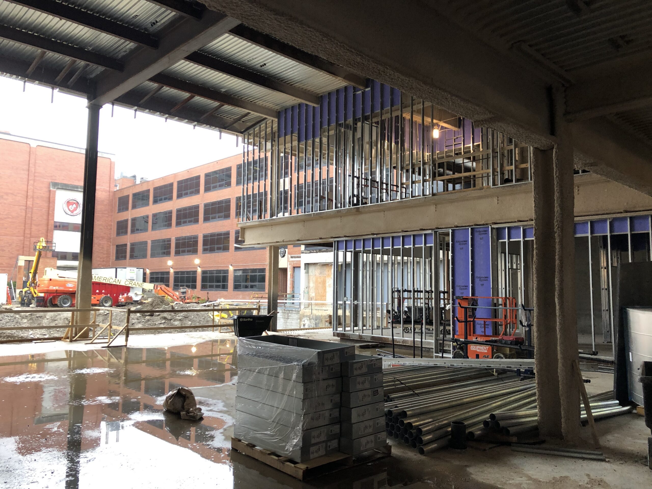 Large building under construction with a lot of construction equipment, including pillars, rods, and other objects