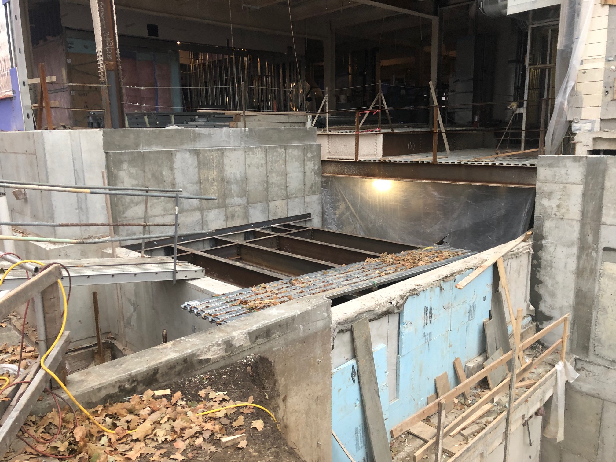 Construction site with a large building under construction, featuring a concrete foundation with a lot of concrete blocks