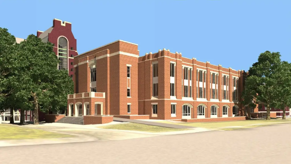 Large brick building with a lot of windows, surrounded by trees and grass